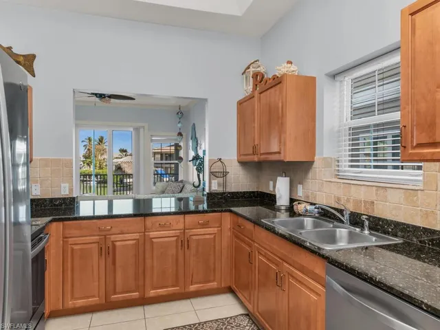 Kitchen with stainless steel appliances, brown cabinets, light tile patterned flooring, and tasteful backsplash