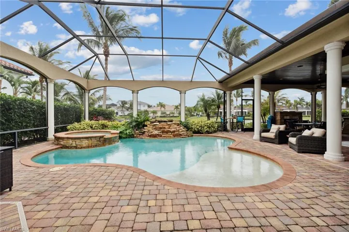 View of pool featuring a patio area, glass enclosure, and an in ground hot tub