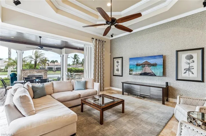 Living room featuring decorative columns, ceiling fan, and ornamental molding
