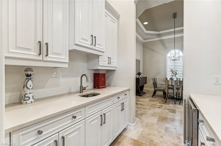 Kitchen with white cabinetry, sink, decorative light fixtures, crown molding, and decorative backsplash