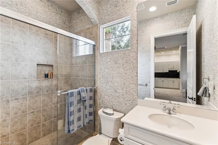 Bathroom with vanity, toilet, and a shower with door