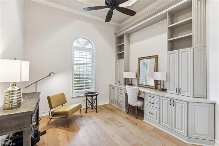 Office area with built in desk, light hardwood / wood-style flooring, a wealth of natural light, and ornamental molding