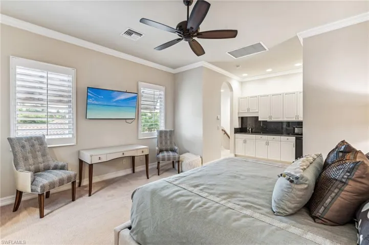 Bedroom with ornamental molding, multiple windows, light carpet, and ceiling fan