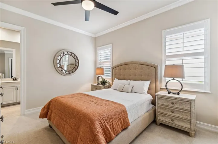 Carpeted bedroom featuring ensuite bathroom, ceiling fan, sink, and ornamental molding