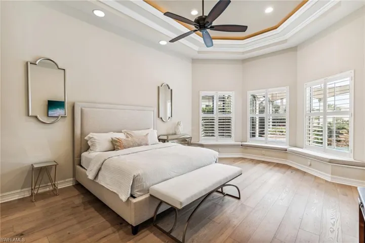 Bedroom with hardwood / wood-style floors, ceiling fan, multiple windows, and crown molding