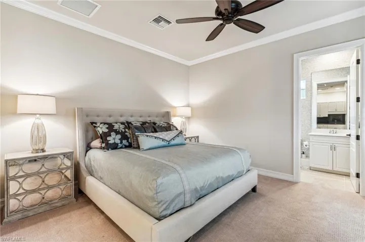 Carpeted bedroom featuring ensuite bathroom, ceiling fan, sink, and ornamental molding