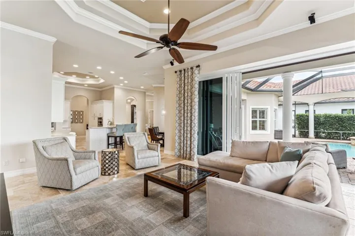 Living room with decorative columns, ceiling fan, and crown molding
