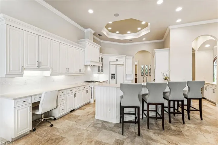 Kitchen with white cabinets, a kitchen bar, paneled built in fridge, and built in desk