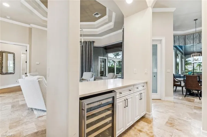 Bar with white cabinetry, beverage cooler, and crown molding