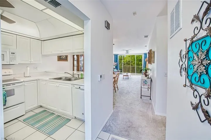 Kitchen featuring white cabinets, light countertops, a ceiling fan, a sink, and white appliances