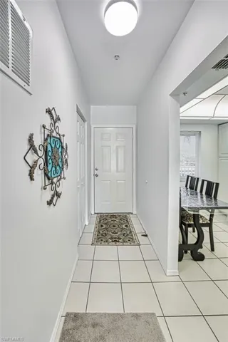 Doorway to outside featuring baseboards, visible vents, and light tile patterned flooring