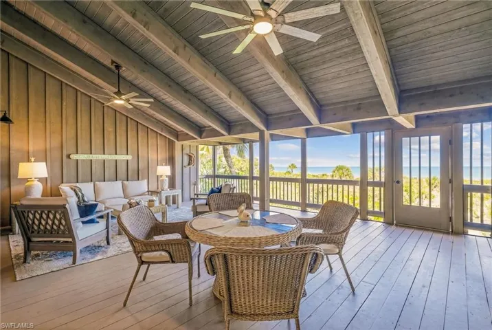 Sunroom / solarium with ceiling fan, a wooden deck, lofted ceiling with beams, and outdoor lounge area