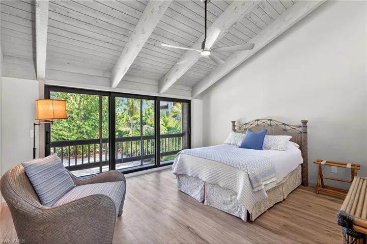 Bedroom with vaulted ceiling with beams, light wood-style flooring, and access to exterior