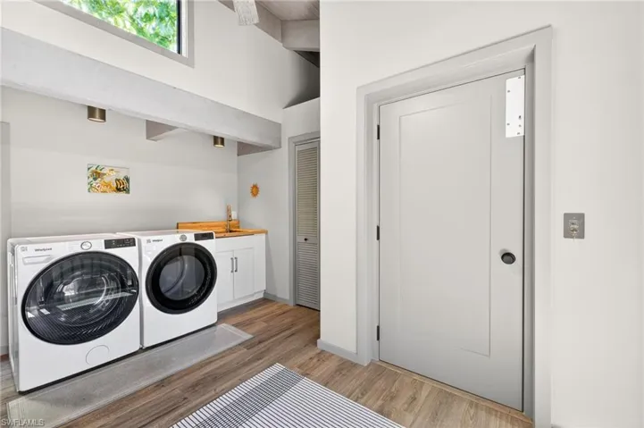Laundry area with light wood-style flooring, independent washer and dryer, and cabinet space