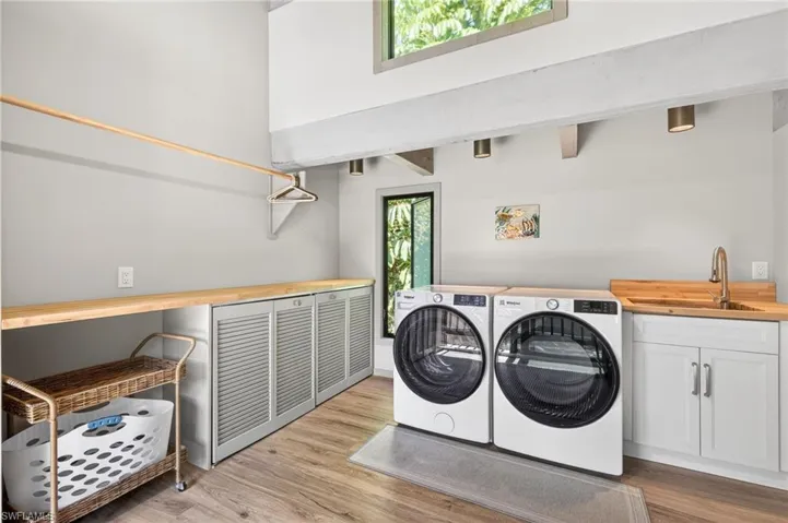 Laundry area featuring independent washer and dryer, light wood-type flooring, and cabinet space