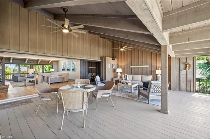 Sunroom / solarium with ceiling fan, a wooden deck, lofted ceiling with beams, and outdoor lounge area