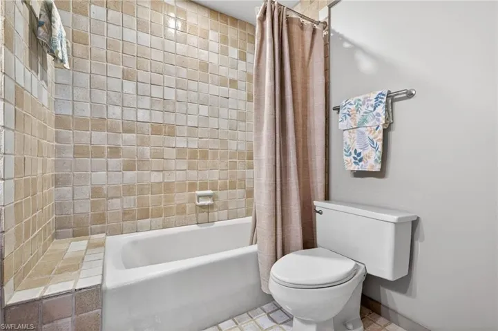 Bathroom with toilet and shower / tub combo with curtain
