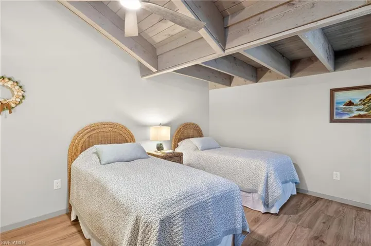 Bedroom with light wood-type flooring and a wood ceiling with exposed beams