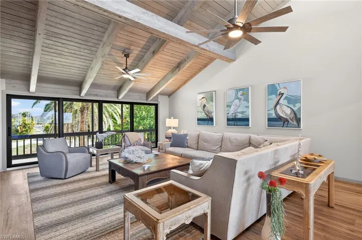 Living room featuring wood finished floors, a ceiling fan, and a high wood beamed ceiling