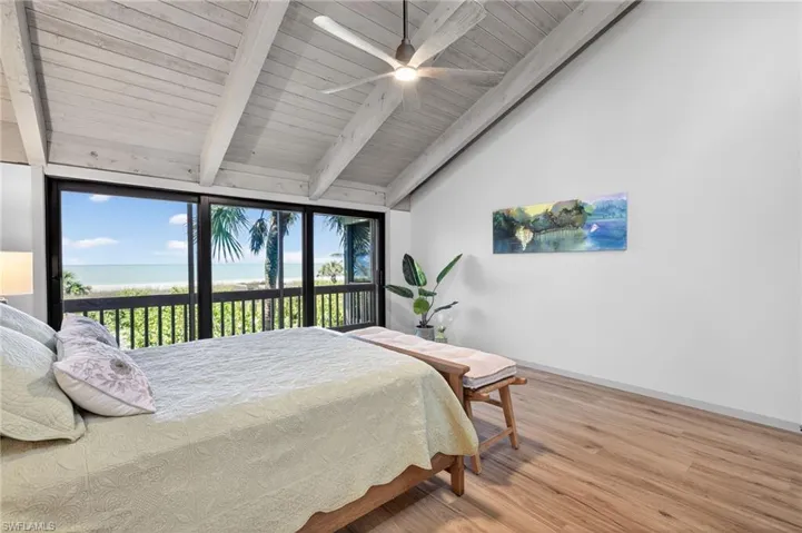 Primary Bedroom featuring light wood-type flooring, a water view, a ceiling fan, vaulted ceiling with beams, and access to outside