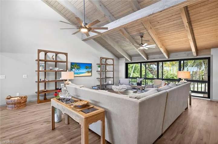 Living room featuring wood finished floors, a high wooden beamed ceiling, and a ceiling fan