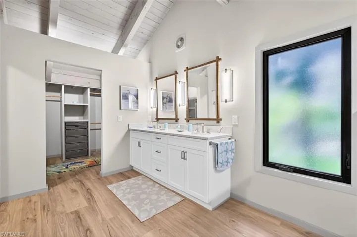 Primary Bathroom with double vanity, light wood-style floors, lofted ceiling with beams, and wood ceiling
