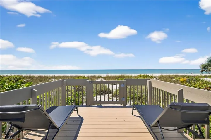 Wooden deck with view of water and beach
