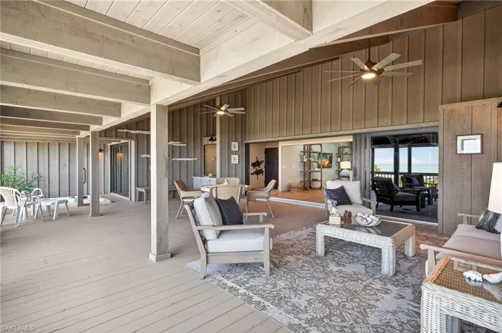 Sunroom / solarium with ceiling fan, a wooden deck, lofted ceiling with beams, and outdoor lounge area