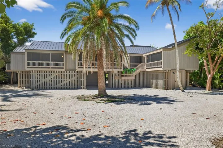 View of front of home with a sunroom, gravel driveway, a metal roof, and an attached garage