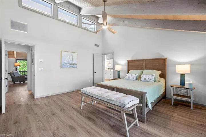 Primary Bedroom featuring wood finished floors, a high wooden beamed ceiling, and ceiling fan