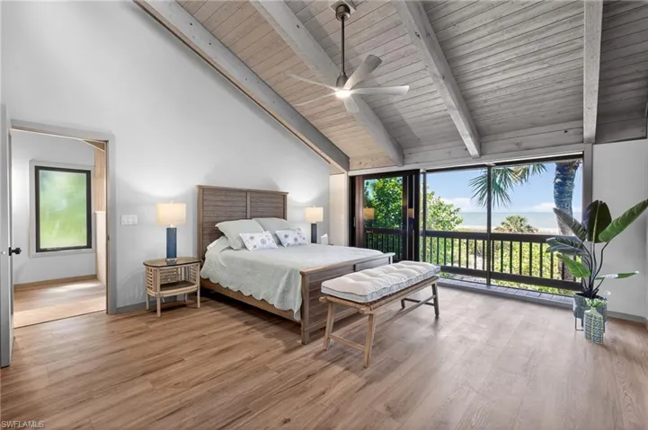 Bedroom with light wood-style floors, ceiling fan, access to outside, and a high wooden beamed ceiling