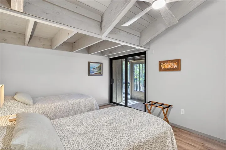 Bedroom with access to outside, light wood-style floors, and a wood ceiling with exposed beams
