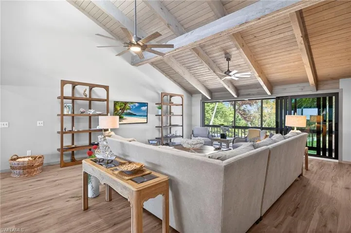 Living area with wood finished floors, a high wooden beamed ceiling, and ceiling fan