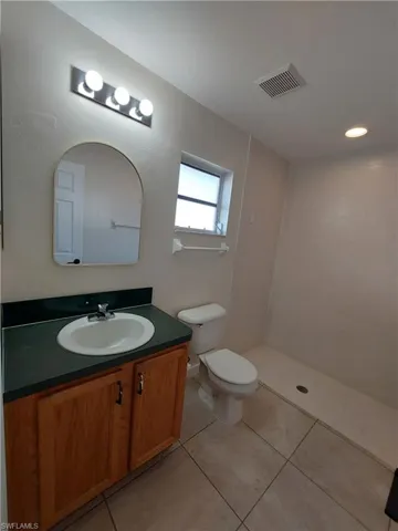 Bathroom with vanity, light tile patterned flooring, and tiled shower