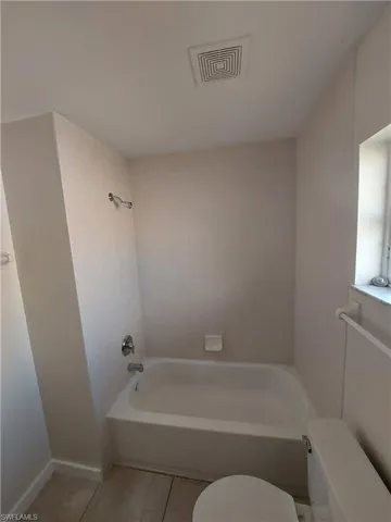 Bathroom with shower / bath combination and light tile patterned flooring