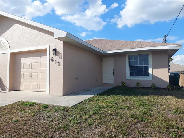 Ranch-style home with a garage, stucco siding, a front lawn, and roof with shingles