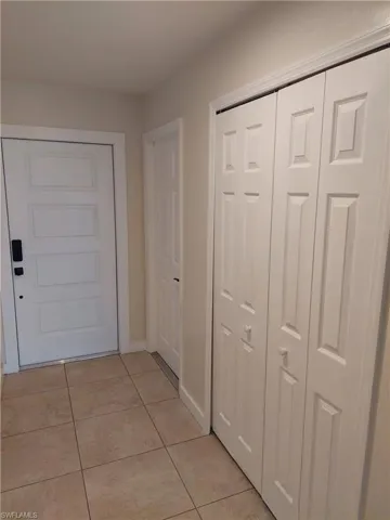 Corridor featuring light tile patterned floors and baseboards