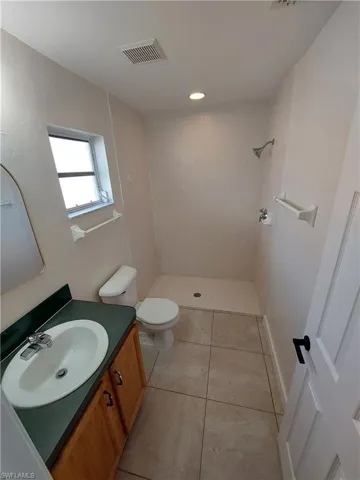 Full bathroom with vanity, a shower stall, light tile patterned floors, and recessed lighting