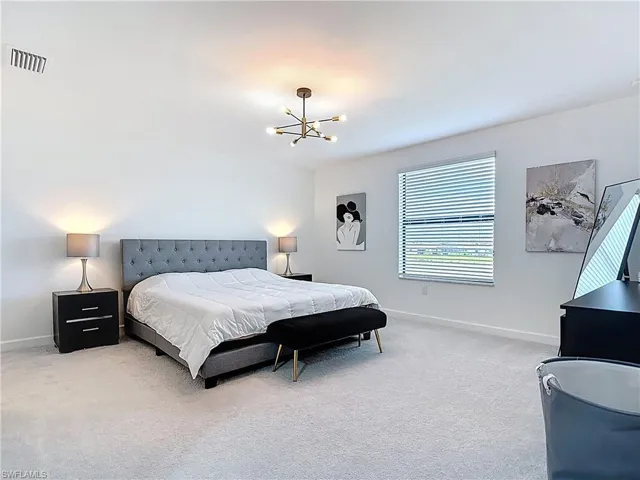 Bedroom with baseboards, a notable chandelier, light colored carpet, and visible vents