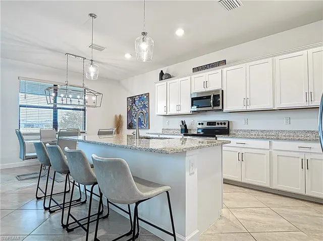Kitchen with a sink, appliances with stainless steel finishes, white cabinets, and visible vents