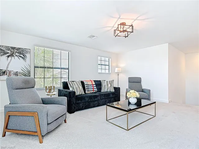 Carpeted living area with baseboards and visible vents