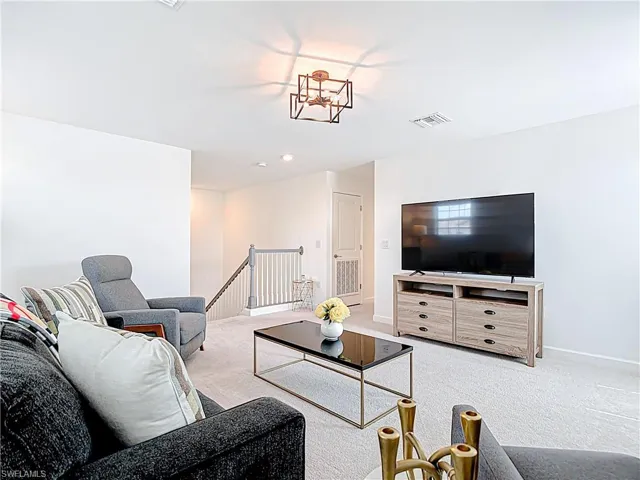 Carpeted living room featuring baseboards and visible vents
