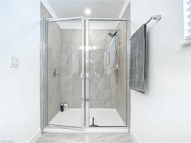 Full bath featuring baseboards and a shower stall