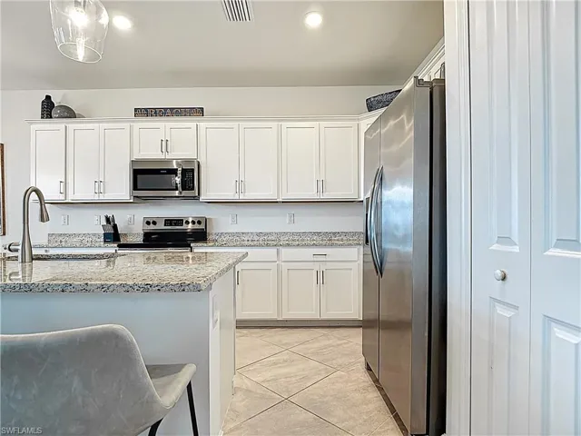 Kitchen with visible vents, marble finish floor, white cabinetry, a sink, and appliances with stainless steel finishes