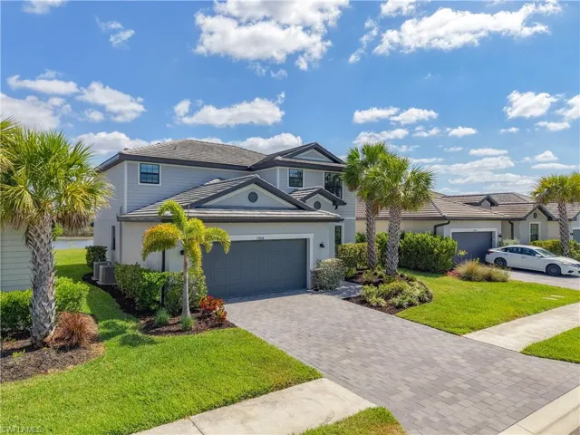 Traditional-style house featuring a garage, a front lawn, decorative driveway, stucco siding, and central AC unit