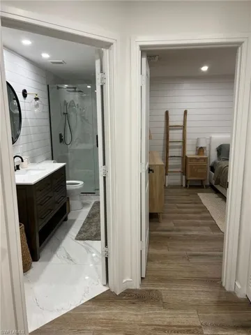 Two distinct spaces featuring wood-finish flooring in the foreground and white shiplap walls