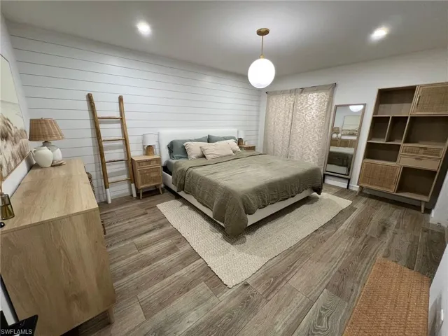 Bedroom featuring wood-finish flooring, a shiplap accent wall, and recessed ceiling lighting