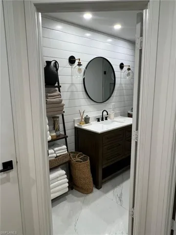 Bathroom featuring a dual-sink vanity with white countertop, dark wood-finish cabinetry, and matte black fixtures