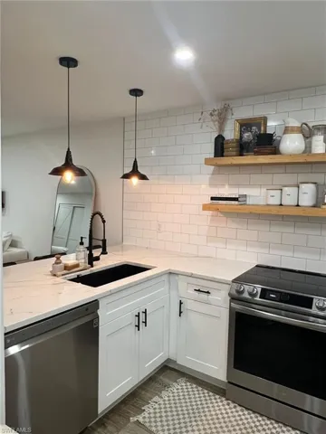 Modern kitchen featuring white shaker cabinetry with black hardware, white stone-finish countertops, and a subway tile backsplash