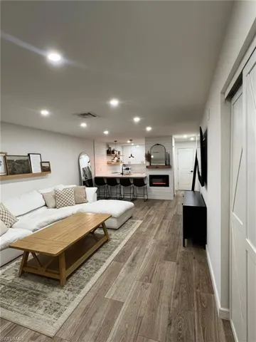 Open-concept living area featuring wood-finish flooring, recessed lighting, and a built-in fireplace